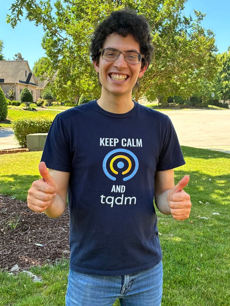 The author smiling and giving a double thumbs up outdoors, wearing his tqdm shirt